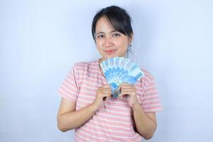 portrait de une Jeune asiatique femme en portant en espèces argent factures souriant sur blanc Contexte photo