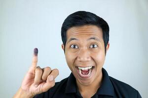 souriant indonésien homme montrant peu doigt après vote sur l'indonésie présidentiel élection photo