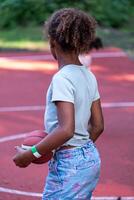 arrière vue de une africain américain fille en portant une basketball sur le rechercher, prêt à jouer, capturer une moment de anticipation et esprit sportif, des sports Activités de une Jeune âge. photo