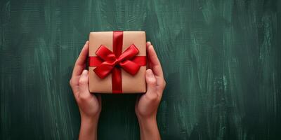 deux mains en portant une enveloppé cadeau boîte avec une rouge arc photo