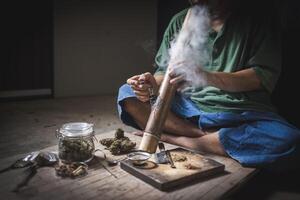 une homme prépare marijuana sur une Coupe planche à fumée, la personne qui fume drogues, drogue toxicomane, drogues dépendance et Retrait symptômes concept. drogueinternational journée contre drogue abus. photo