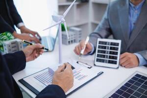 les hommes d'affaires, investisseurs et électrique ingénieurs discuter nettoyer énergie Résidentiel projets Aidez-moi réduire global chauffage et utilisation nettoyer énergie de vent et lumière du soleil. concept nettoyer énergie projets photo