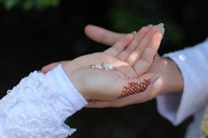 une paire de anneaux sur le mains de le la mariée et jeune marié photo