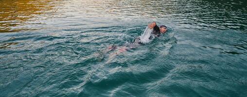 une professionnel triathlète les trains avec inébranlable dévouement pour un A venir compétition à une lac, émanant une sens de athlétisme et profond engagement à excellence. photo