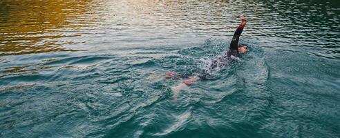 une professionnel triathlète les trains avec inébranlable dévouement pour un A venir compétition à une lac, émanant une sens de athlétisme et profond engagement à excellence. photo