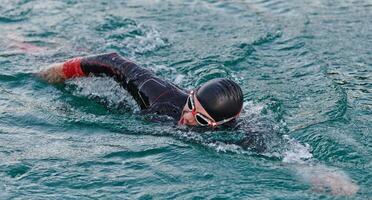 une professionnel triathlète les trains avec inébranlable dévouement pour un A venir compétition à une lac, émanant une sens de athlétisme et profond engagement à excellence. photo