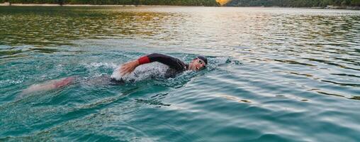 une professionnel triathlète les trains avec inébranlable dévouement pour un A venir compétition à une lac, émanant une sens de athlétisme et profond engagement à excellence. photo