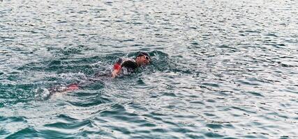 une professionnel triathlète les trains avec inébranlable dévouement pour un A venir compétition à une lac, émanant une sens de athlétisme et profond engagement à excellence. photo