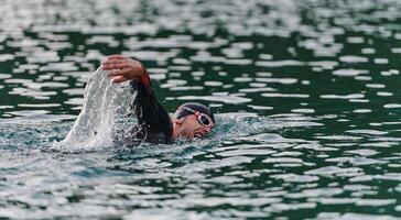 une professionnel triathlète les trains avec inébranlable dévouement pour un A venir compétition à une lac, émanant une sens de athlétisme et profond engagement à excellence. photo