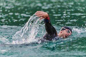 une professionnel triathlète les trains avec inébranlable dévouement pour un A venir compétition à une lac, émanant une sens de athlétisme et profond engagement à excellence. photo