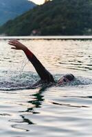 une professionnel triathlète les trains avec inébranlable dévouement pour un A venir compétition à une lac, émanant une sens de athlétisme et profond engagement à excellence. photo