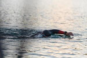 une professionnel triathlète les trains avec inébranlable dévouement pour un A venir compétition à une lac, émanant une sens de athlétisme et profond engagement à excellence. photo