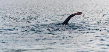 une professionnel triathlète les trains avec inébranlable dévouement pour un A venir compétition à une lac, émanant une sens de athlétisme et profond engagement à excellence. photo