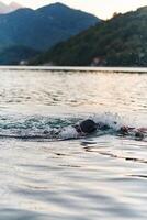 une professionnel triathlète les trains avec inébranlable dévouement pour un A venir compétition à une lac, émanant une sens de athlétisme et profond engagement à excellence. photo