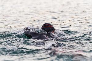 une professionnel triathlète les trains avec inébranlable dévouement pour un A venir compétition à une lac, émanant une sens de athlétisme et profond engagement à excellence. photo