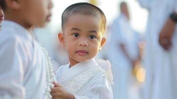 thaïlandais garçon habillé pour aconit initiation, enveloppé dans tradition. robe blanche enfant pendant une sacré cérémonie. concept de culturel rites, jeune spiritualité, et cérémonial tenue. photo