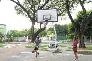 le Masculin et femelle basketball joueurs entraine toi en utilisant le Balle dans le parc tribunal avec diligence et Heureusement. photo