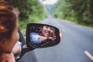 les femmes asiatiques voyagent se détendent pendant les vacances. voyager en parking. heureusement avec la nature, forêt rurale. en été. femme au volant d'une voiture voyageant heureusement. photo