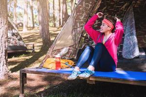 jeune femme en tenue de sport est assise et se détend dans le camping dans la forêt, lagon naturel. photo