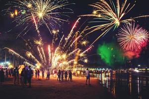 feux d'artifice avec des silhouettes de personnes dans un événement de vacances. feux d'artifice du nouvel an sur la plage. les voyageurs et les gens célèbrent le jour de l'an à kamala beach phuket, thaïlande. photo