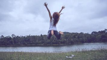 les femmes asiatiques voyagent se détendent pendant les vacances. sauter sur un vert pâturage. photo