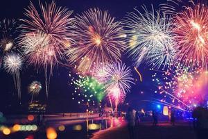 feux d'artifice avec des silhouettes de personnes dans un événement de vacances. feux d'artifice du nouvel an sur la plage. les voyageurs et les gens célèbrent le jour de l'an à kamala beach phuket, thaïlande.