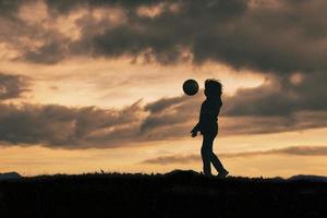 enfant en silhouette dribble avec le football photo