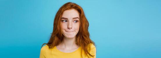 photo du visage portrait de content gingembre rouge cheveux fille avec taches de rousseur souriant à la recherche à caméra. pastel bleu Contexte. copie espace