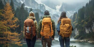 Trois gens avec sacs à dos en marchant par une rivière dans montagnes photo