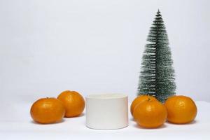 gros plan d'un podium sur fond blanc, décoré d'un arbre de noël et de mandarines. Bonne année et joyeux Noël.
