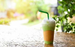 thé vert matcha avec du lait sur verre en plastique sur la table en bois et fond vert nature - smoothie au thé vert photo