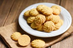 biscuits de petit déjeuner vanille sur plaque blanche et fond en bois, mini biscuits biscuits. photo