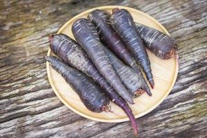 carotte violette sur plaque de bois, carotte fraîche pour la cuisson végétarienne sur la table. photo