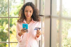 belle femme latine utilisant un smartphone avec carte de crédit photo