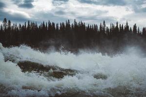 vagues et éclaboussures de rivière de montagne sur fond de forêt et ciel dramatique. paysage d'eau de rivière de forêt. photo