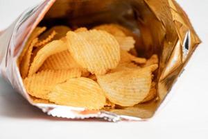 croustilles, délicieux assaisonnements pour barbecue épicés pour les crips, collations frites en fines tranches de restauration rapide dans un sac ouvert. photo