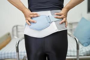 patiente asiatique portant une ceinture de soutien des maux de dos pour lombaire orthopédique avec marchette. photo