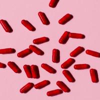 de nombreuses pilules capsules rouges sur un fond coloré. suppléments de santé et médicaments photo