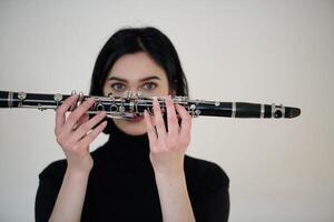 gracieux brunette musicien posant avec clarinette sur blanc Contexte photo