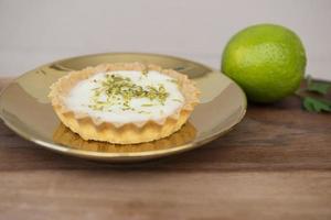 vue latérale d'une tarte au citron sur une assiette avec des tranches de citron sur la table. photo