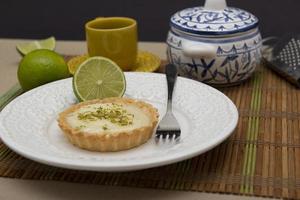 vue latérale d'une tarte au citron sur une assiette avec des tranches de citron sur la table. photo