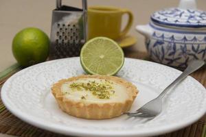 vue latérale d'une tarte au citron sur une assiette avec des tranches de citron sur la table. photo