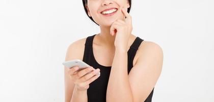 rêver femme souriante tenir le téléphone portable. gros plan jeune heureuse belle femme japonaise asiatique. fille regardant un téléphone portable isolé sur fond blanc. espace de copie. photo