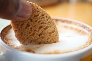 verser des biscuits sucrés dans une tasse à café sur une table en bois photo