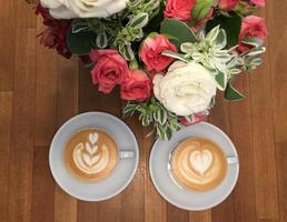 deux cappuccinos avec décorations roses sur une table en bois