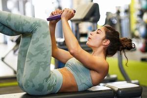 jeune sportive sur tapis de yoga faisant des redressements assis dans une salle de sport. photo