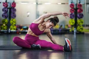 Jeune femme faisant des exercices d'étirement sur un tapis de yoga photo