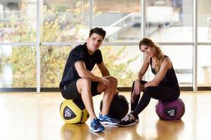 homme et femme assis avec des fitballs dans la salle de gym. photo