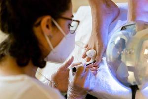 esthéticienne donnant une pédicure peignant les ongles de son client dans un centre de beauté. photo