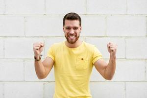 jeune homme drôle sur le mur de briques avec une drôle d'expression. photo